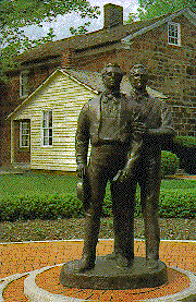 Statue of Joseph and Hyrum Smith with Carthage jail in background