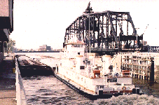 Towboat leaving lock with swinging bridge in background