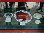 Peking Duck in the window of a famous restaurant.   In its classic form, the dish calls for a specific breed of duck, the Imperial Peking, that is force-fed and housed in a small cage so inactivity will ensure tender meat. After the entrails are removed, the lower opening is sewed shut. Air is forced between the skin and flesh to puff out the skin so that the fat will be rendered out during roasting and the skin, the choicest part of the dish, will be very crisp. The inflated bird is painted with a sweet solution, hung up to dry for several hours, then roasted suspended in a cylindrical clay oven.