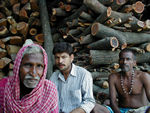 Men sitting in front of wood for cremations