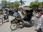 Rickshaw in the bustle of a traffic circle closed to autorickshaws and cars.  Curiously the photo does not show the dirt