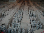 Some of the 6-8 thousand soldiers.  No one is certain that all the soldiers have been found.  The buried army faces east, poised for battle, about three-quarters of a mile from the outer wall of  Shih huang-ti's tomb. In pits nearby have been found the remains of seven humans (possibly the emperor's children), a subterranean stable filled with horse skeletons, an assemblage of half-size bronze chariots, 70 individual burial sites, a zoo for exotic animals, and other artifacts.  Today, most of the surface area consists of farm fields, buildings, roads, etc.