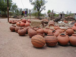 Pots and behind them the pits used as kilns and the wood and cow dung used for fuel