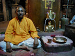 The "priest" with the lingam behind him.  In Hinduism, the lingam, symbol of the god Shiva, is worshipped as an emblem of generative power. Although not all simple columns, the ones we have seen have all been stylized.  As the symbol of male creative energy the lingam is combined with its female counterpart, the yoni - a uterus-shaped stone "basin" from which the lingam rises. Although the lingam originally may have had no relation to Shiva, it has from ancient times been regarded as symbolizing Shiva's creative energy and is widely worshiped as his fundamental form.  Often Shiva temples, unlike those of other gods - Hanuman for instance - have no anthropomorphic representation of Shiva.