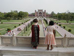 Maggie, dressed in Indian garb, and an Indian girl, dressed in Western garb, standing in front of the mausoleum and looking across the garden to the main gateway.